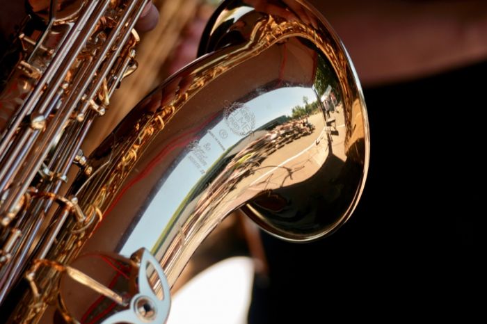 Publikum und Bootshaus spiegeln sich verzerrt im Messing eines Saxophons.