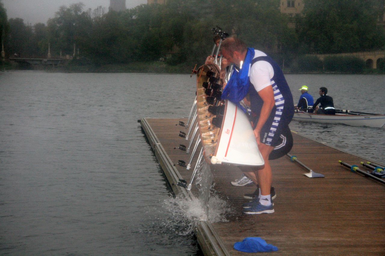 Rudermannschaft kippt Wasser aus dem Boot.