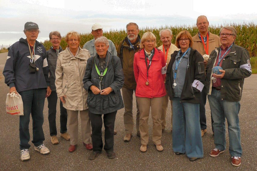 Männer und Frauen stehen mit Boßelkugeln auf einem Asphaltweg. Die Teilnehmer des SRG-Boßel-Turniers 2015.